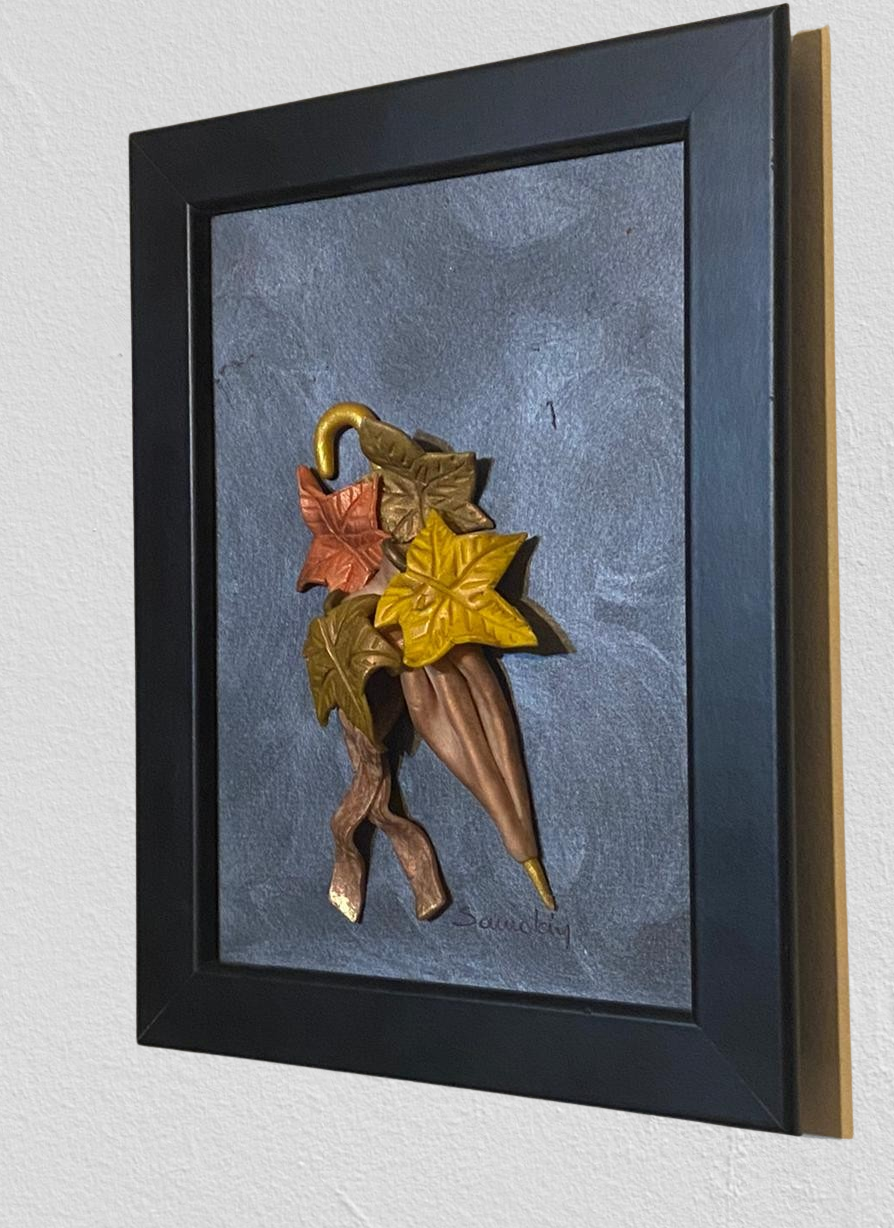 Autumn wall frame. It portraits four leaves in bronze, golden brown and olive green with an bronze umbrella.  All of the elements are in 3D form and crafted with polymer clay. The background is painted in industrial gray and the frame is black.